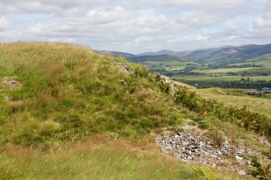 View across windswept grass from Beattock hill fort towards the Moffat hills and forestry, Dumfries and Galloway, Scotland, UK