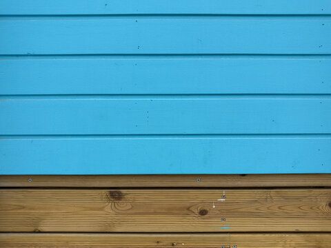 Bright blue wooden siding meets natural brown wood decking in a clean horizontal composition.