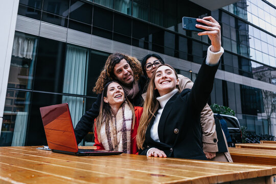 hispanic business teamwork with different ages working and taking a photo selfie together outdoors in winter at public park in city. Diverse latin Entrepreneurs and multigenerational teamwork 
