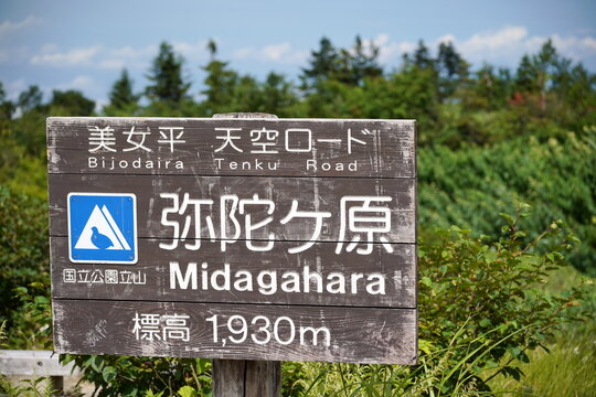 富山県の立山黒部アルペンルートにある弥陀ヶ原（みだがはら）の案内看板。標高1930メートルを示し、周囲には豊かな緑と青空が広がっている。