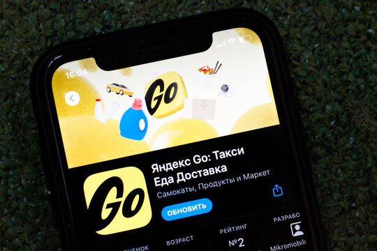 Russian multiservices Yandex Go (Яндекс Go) app on iPhone screen. Delivery and taxi app, vibrant yellow color. Modern technology in everyday life