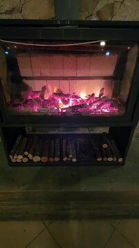 Realistic vertical stock footage of a cozy indoor wood-burning fireplace with vivid flames and glowing embers, firewood below, warm rustic home atmosphere, relaxing winter ambiance