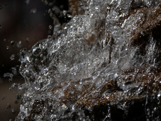 Clear Water Splashing Over Dark Rock Surface Close Up © Sergei