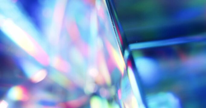 Light reflecting glass in brilliant saturated colors. Radiant lighting through a prism cube creating a visual of a colorful rainbow effect of light refraction. Spinning geometric abstract background.