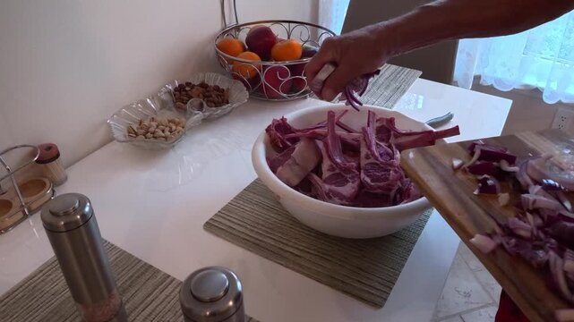 Raw lamb ribs (rack or bone-in ribs) are shown being marinated with sliced onion.