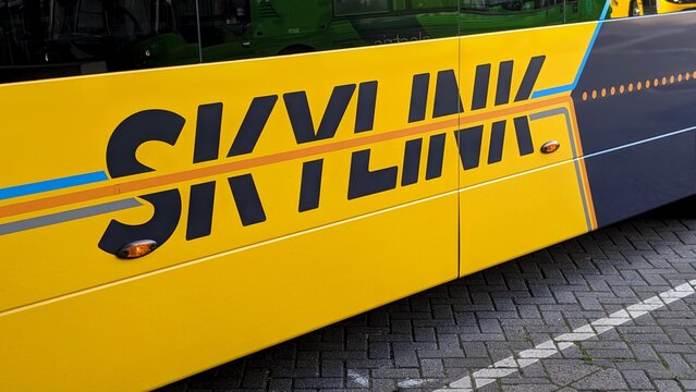 Leicester, England, UK - 23 September 2026: Yellow Skylink city bus side panel closeup with bold black lettering and orange blue stripes on brick pavement