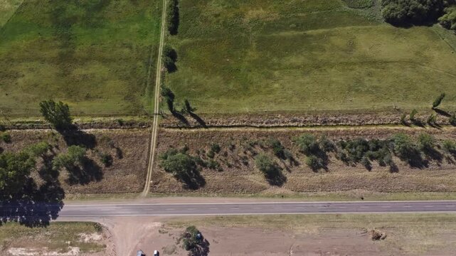 Aerial 4K drone descending reveal of the endless flat plains of La Pampa with a rural road, Argentina