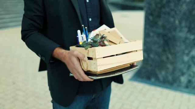 Fired white collar worker standing outside office holding box. Job loss shock and despair