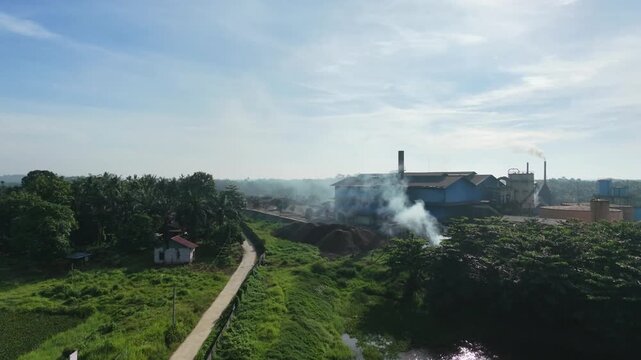 Panoramic aerial landscape showing a palm oil industrial processing plant located in the center of endless green plantation trees and ponds. Agricultural business and economy.