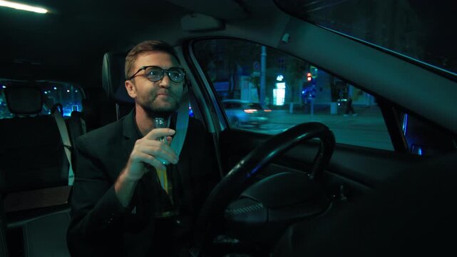Careless driver drinking beer bottle behind steering wheel at night. Highway safety danger
