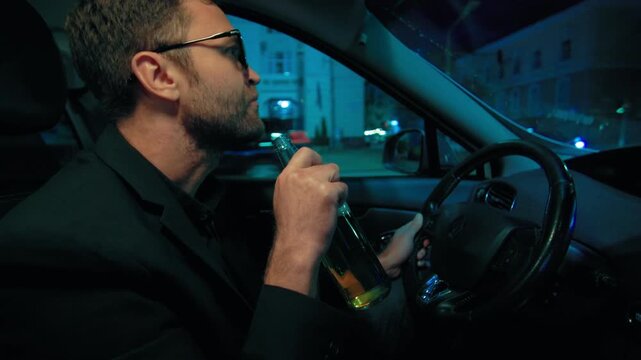 Dangerous driver drinking beer from bottle while operating car. Substance abuse traffic crime