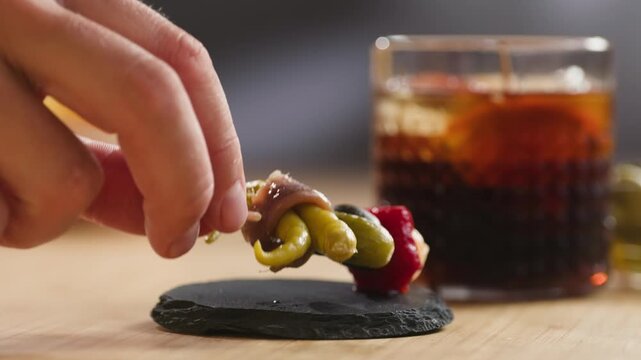 Gilda pintxo, traditional Spanish tapas with hot green pepper, anchovy, olives and pickled vegetables, served with vermouth