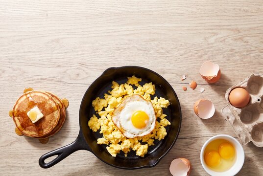 Breakfast with scrambled eggs and pancakes on a wooden table