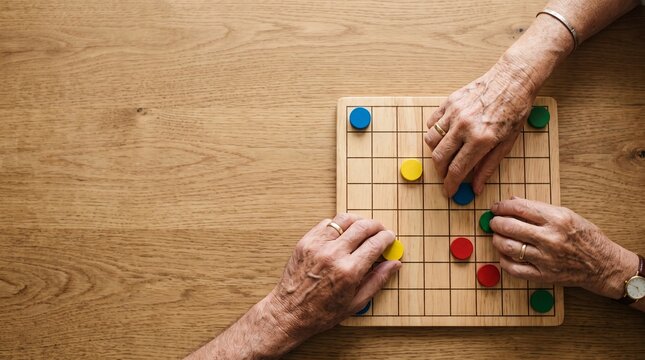 テーブルゲームの駒を一手ずつ進めるシニアの手元と集中して楽しむ頭の体操