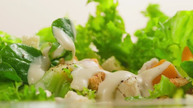 Caesar Dressing or Creamy Sauce Pouring Over Fresh Green Caesar Salad Leaves in Bowl, Close Up of Healthy Food Preparation, Restaurant and Cafe Cooking Concept
