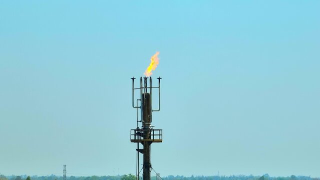 Drone view capturing a refinery flare tower with active flame combustion, symbolizing oil and gas operations, energy infrastructure, and industrial emissions within the global petroleum industry. 4k.
