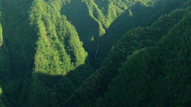 Aerial view of Sacred Falls waterfall tucked in lush green Koʻolau mountain valley, Oahu Hawaii