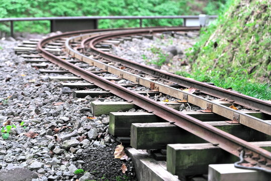 Miniature railway tracks curving through green park scenery