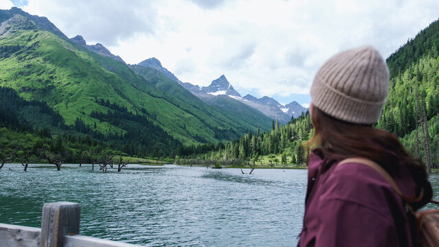 Rear view of a woman looking at a beautiful lake and mountain views in summertime, Chengdu, China