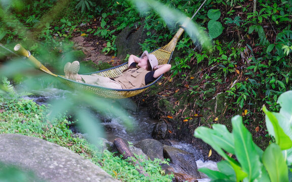 A woman lying and relaxing in wooden hammock in the creek