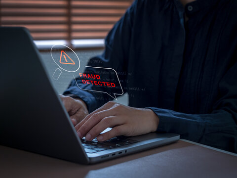 Security analyst using laptop computer with fraud detected warning interface. Real-time transaction monitoring, suspicious activity detection, financial security and digital fraud prevention concepts.