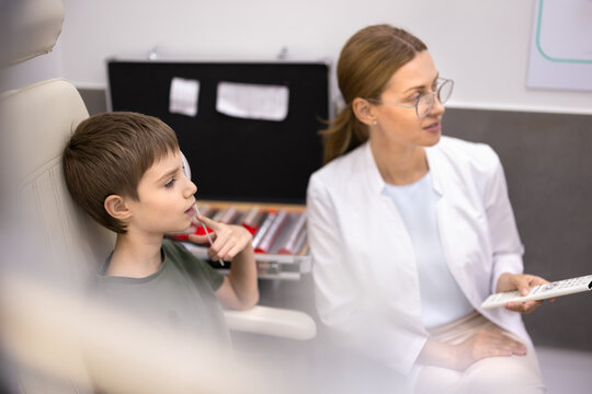 Child passing professional visual acuity test during medical consultation with female ophthalmologist in ophthalmology clinic. Vision assessment, preventive eye care, eyesight examination procedure
