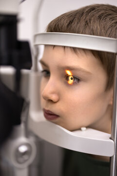 Child boy during slit lamp vision screening with bright examination light reflecting pupil, closeup. Professional pediatric eyesight health diagnostics, preventive eye care, vision protection concept