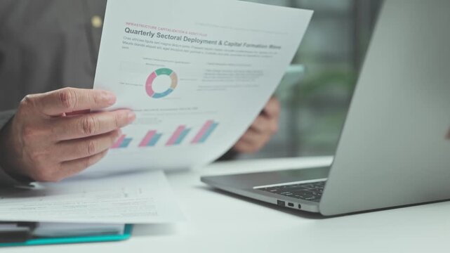 Focused audit professional performs audit procedures while financial analysis validates analysis reports beside open laptop computer.