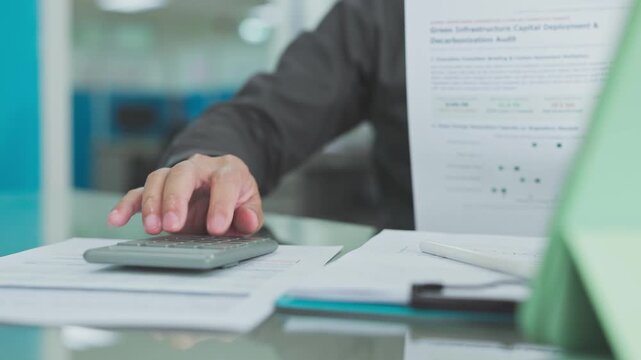Accountant conducts financial audit procedures on report paperwork, executing meticulous audit calculations that advance strategic financial planning.