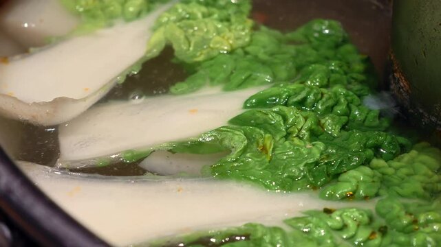 Close-up view of fresh Chinese cabbage boiling in hot pot clear broth