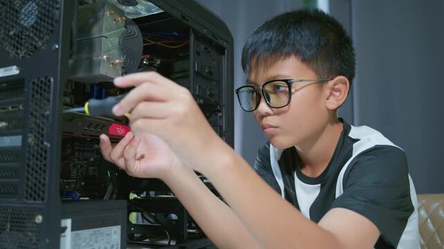 Young boy concentrating while repairing and assembling hardware inside an open desktop computer case at home, learning technology and problem solving skills