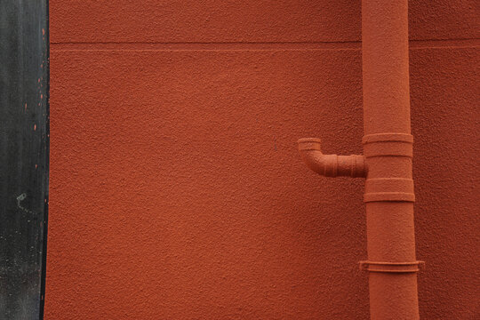 Close-up view of a red wall with a vertical pipe