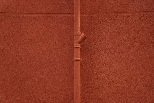 Close-up view of a red wall with a vertical pipe