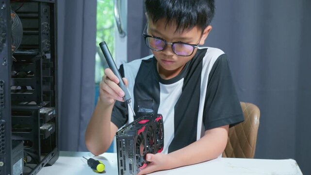 Young boy concentrating while repairing and assembling hardware inside an open desktop computer case at home, learning technology and problem solving skills