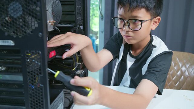 Young boy concentrating while repairing and assembling hardware inside an open desktop computer case at home, learning technology and problem solving skills