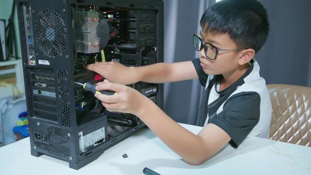 Young boy concentrating while repairing and assembling hardware inside an open desktop computer case at home, learning technology and problem solving skills