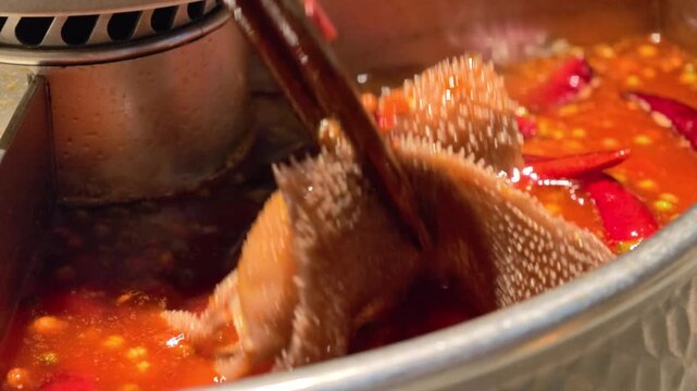 slow motion, close-up of tripe hot pot with red oil soup base, tripe, and red chilies.