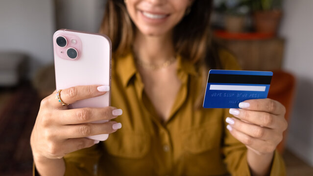Closeup cropped view female customer e-shopping, ordering goods, making secure online payment with smartphone and credit card at home. Electronic commerce, mobile banking, digital finances concept