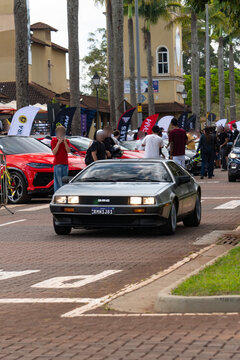 Silver DMC DeLorean Sports Car Front View Driving On Paved Outdoor Event Street