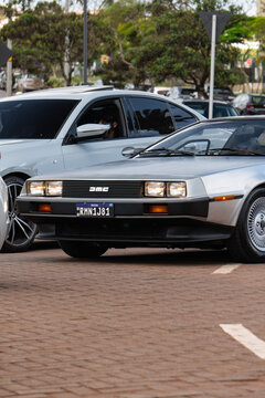 Silver Stainless Steel DMC DeLorean Sports Coupe Front View Driving On Paved Urban Street