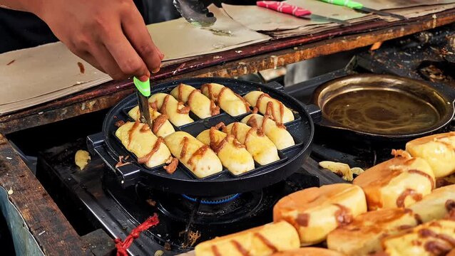 Chef preparing delicious kue pukis cake on hot waffle iron mold at local street market, culinary snack process. 4K