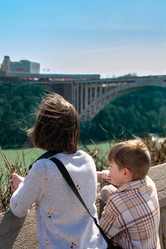 Sister and brother sitting on the grass in a park and eating food