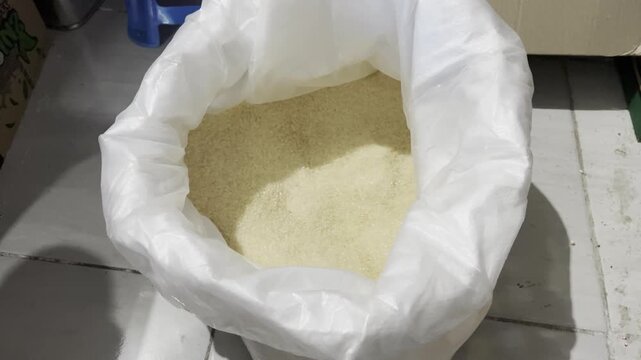 Raw granulated sugar crystals inside open woven sack