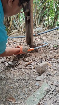 Young Man Cutting Rusted Iron Pipe Near Ground Level