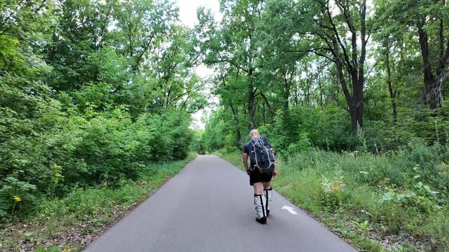 A dedicated man trains in a lush forest, carrying a 50 kg backpack. He wears climbing boots and follows a winding path, pushing his limits in the great outdoors.