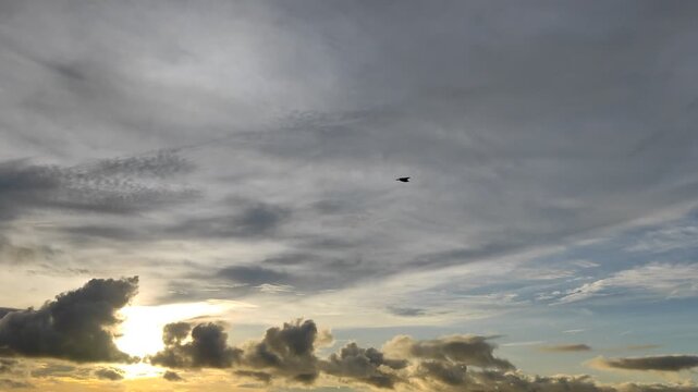 Sunset sky with dark clouds and glowing sun rays breaking through or sunrise scenery over the horizon with cloud