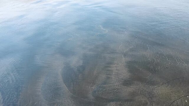 Wet ocean sand at the water edge with gentle tidal wave receding from the beach waves tide shoreline coast seashore waves tide shoreline coast seashore
