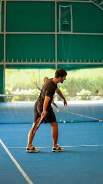 A young man playing padel on a blue indoor court with a racket in his hand during a match