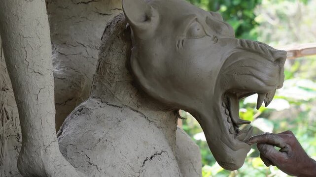 Artisan sculpting a traditional clay lion statue for durga puja