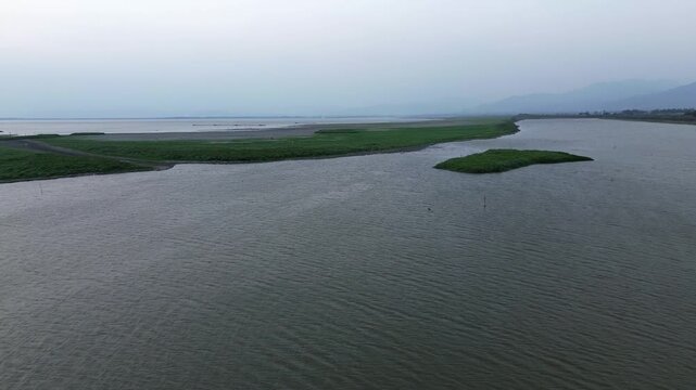 Serene Lake with Grassy Island and Distant Mountains